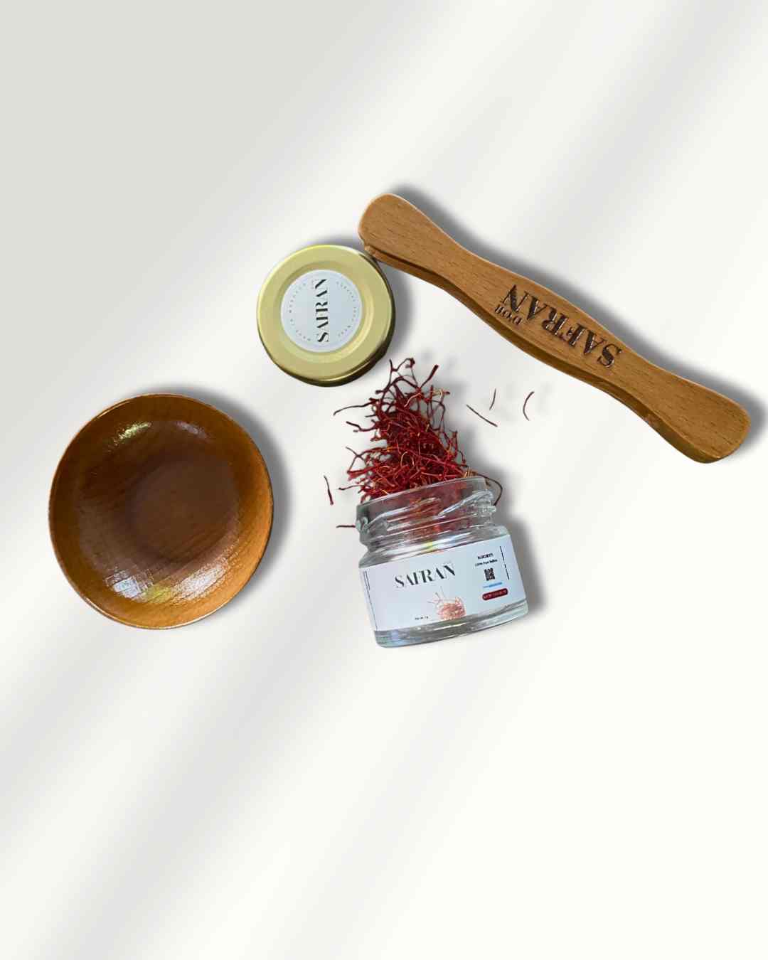 Saffron packaging set with a wooden bowl, saffron jar, and spoon on a white background